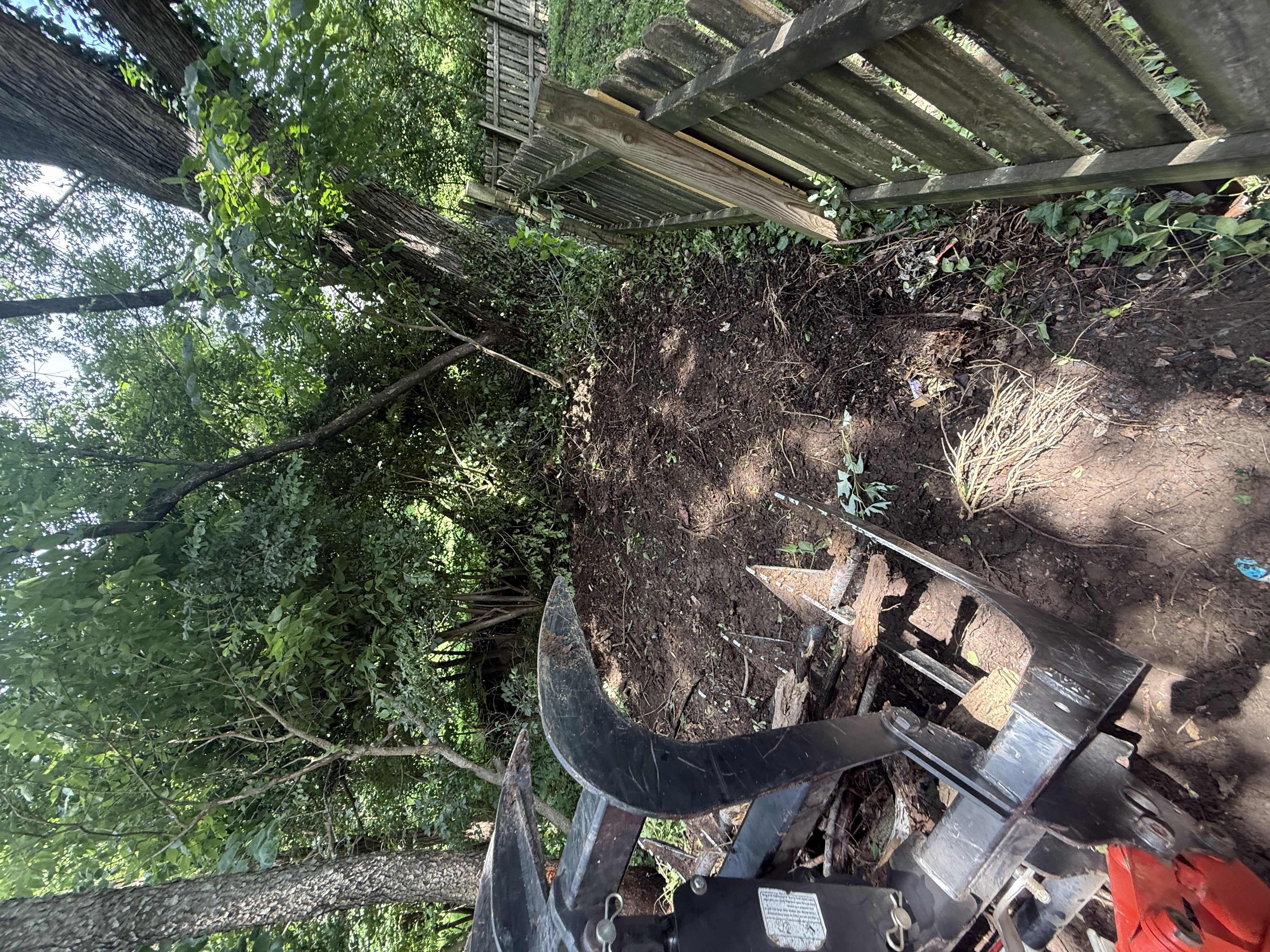 Mini excavator clearing stump and roots along fence line