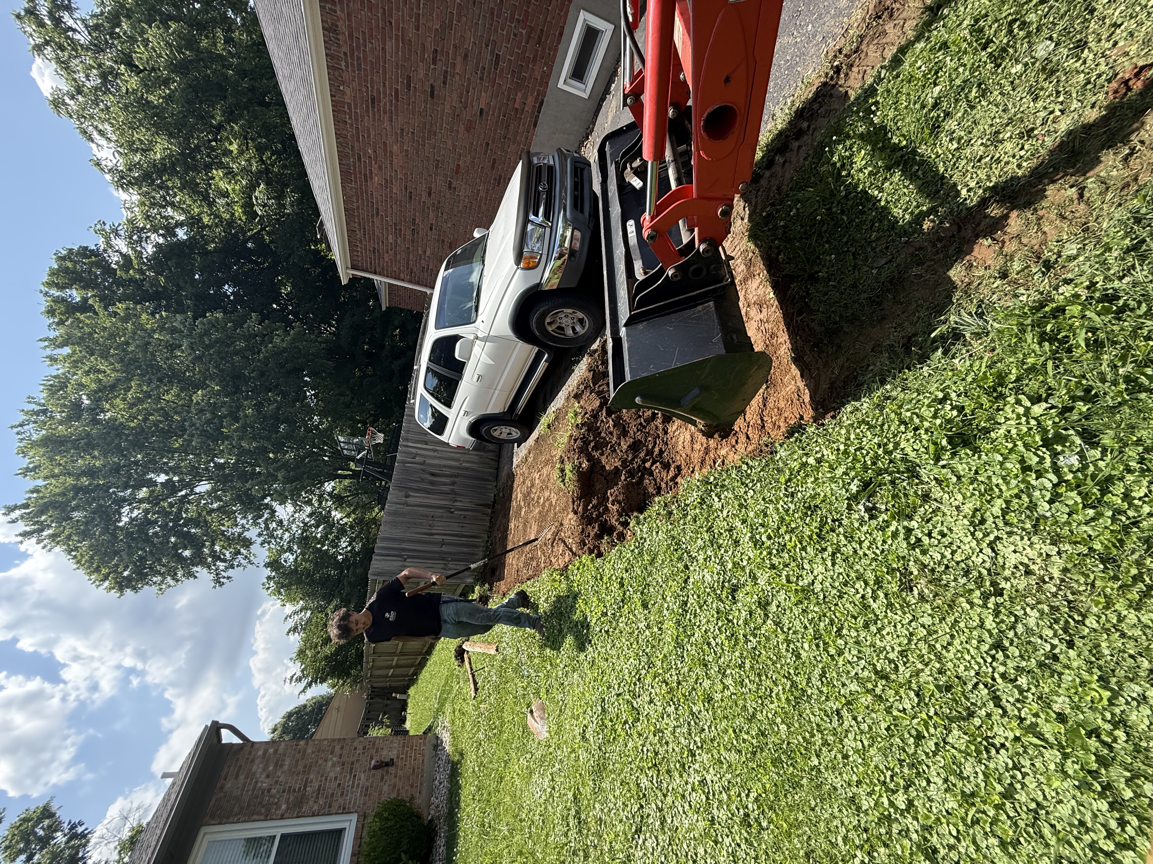 Excavator trenching along house foundation