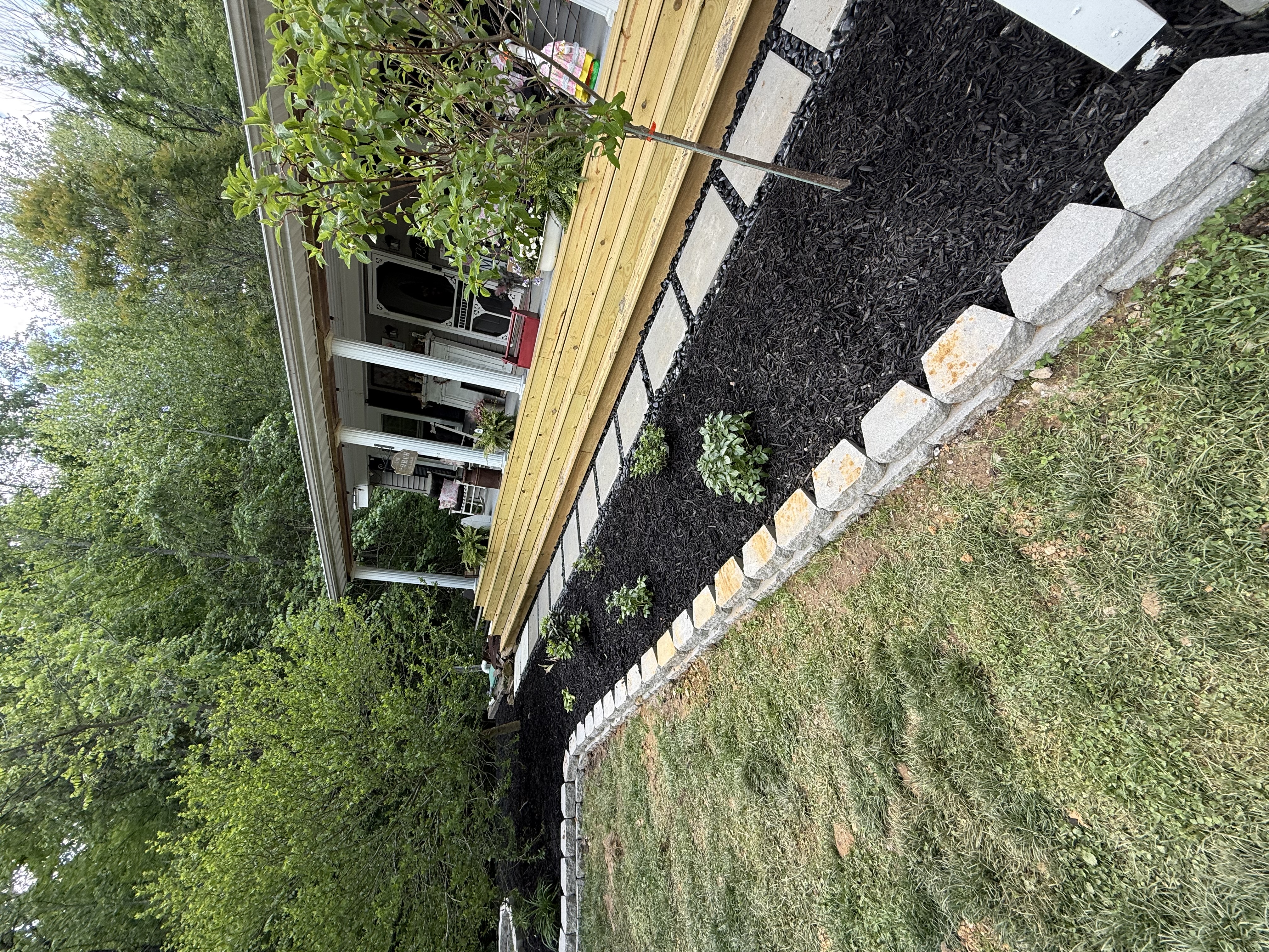 Completed stone border with mulch bed along deck